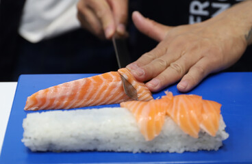 chef experto en sushi cortando Salmon ahumado para la elaboración de sushi con cuchillo especial y manos