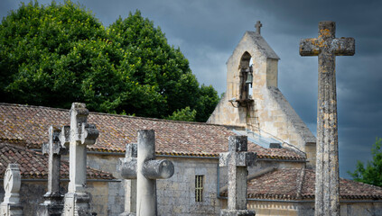 A cemetery filled with ornate stone crosses stands adjacent to a historic church in...