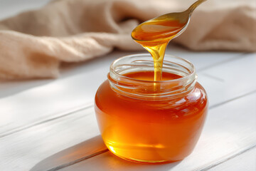 Honey dripping from a spoon into a jar