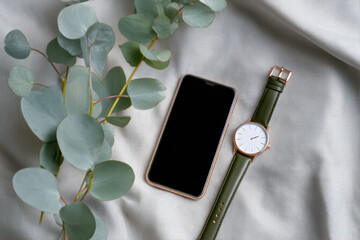 Smartphone, watch, and plants on fabric
