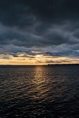 sunset over Lake Constance Bodensee with dark clouds and a small stripe of golden backlight seen from Bregenz 