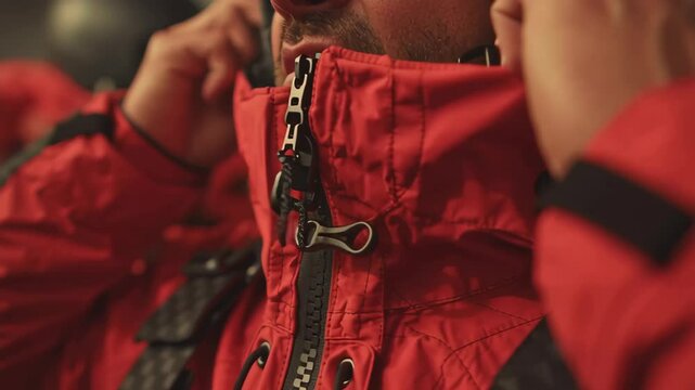 Rescue team members preparing for an emergency operation, meticulously zipping up protective gear while fostering a tense and focused atmosphere filled with determination and teamwork