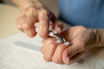 Nail care at home, close-up manicure. Using cuticle nippers, a nail file, a sanding pad, a brush and an orange stick