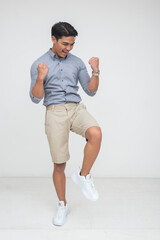 Young Asian man jumps in joy with fists up