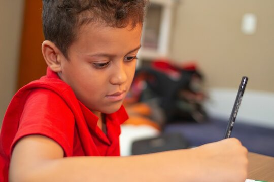 Young boy focused on drawing indoors.