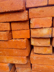 Pile of red bricks on a construction site to build a brick wall of a house.