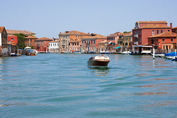 Murano, Province of Venice, Italy, June 14th, 2025. Speedboat cruising through canal surrounded by...