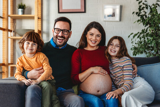 Happy family with pregnant mother and cute children have a fun at home and hug each other