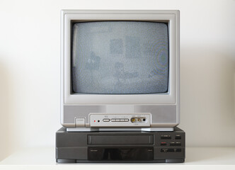 Old silver vintage television with static on screen and VCR from 1980s, 1990s, 2000s isolated on white background.