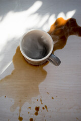 Coffee cup on wooden table with shadow from the window.