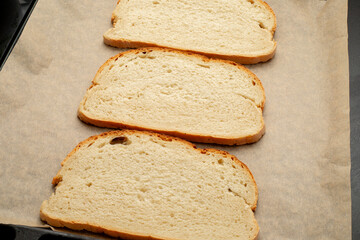 Close-up of tomato bruschetta on artisan bread slices with fresh sliced ​​tomatoes, parmesan cheese and herbs on a baking sheet in the oven while cooking. Food preparation process, bruschetta, sandwic
