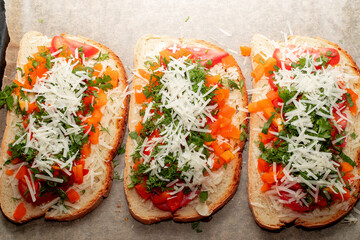 Close-up of tomato bruschetta on artisan bread slices with fresh sliced ​​tomatoes, parmesan cheese and herbs on a baking sheet in the oven while cooking. Food preparation process, bruschetta, sandwic