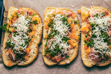 Close-up of tomato bruschetta on artisan bread slices with fresh sliced ​​tomatoes, parmesan cheese and herbs on a baking sheet in the oven while cooking. Food preparation process, bruschetta, sandwic