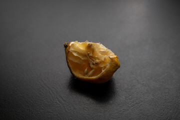 A piece of bad dry lemon isolated on black background.