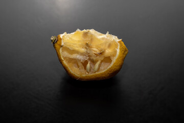 A piece of bad dry lemon isolated on black background.