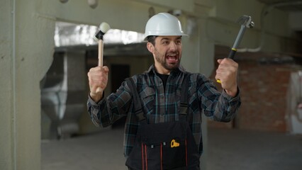 Builder emotional man Caucasian guy engineer repairman holding hammers tools repair work industry...