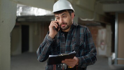 Caucasian man foreman builder talking mobile phone on construction site problem building stressed...