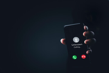 Hand holding mobile phone with unknown caller notification, concept of telephone fraud, call blocking, digital security, unwanted calls, anonymous communication, phishing attempt.
