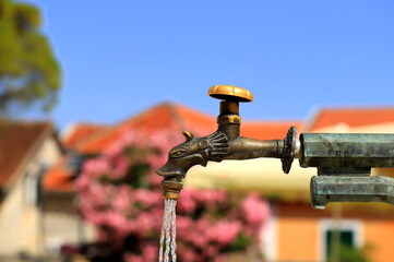 Antique water tap at fountain in the old town of Herceg Novi, Montenegro. Water flows from a...