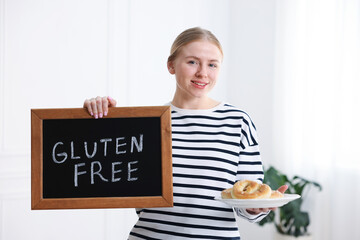 Woman holding small chalkboard with text Gluten Free and pretzels indoors