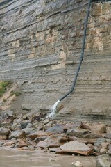 Water Flowing from Black Pipe on Coastal Cliff in Stormy Weather