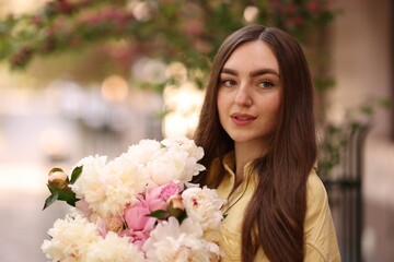 Fototapeta premium Woman with bouquet of beautiful peonies on city street