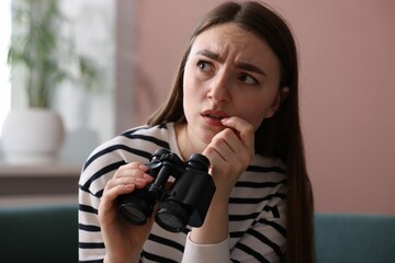 Paranoia. Worried man with binoculars at home