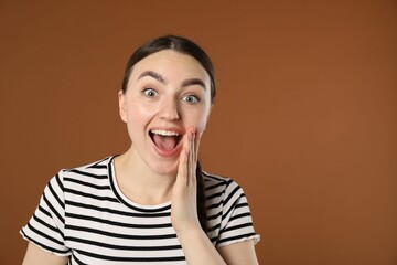 Portrait of surprised woman on brown background, space for text