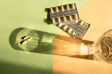 Capsules and blisters with capsules on a light background of orange and green