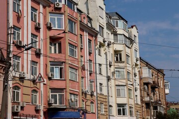 Street View of Residential Buildings in Urban Area with Parked Cars, Traffic Signs, and Varied Architectural Facades