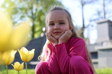Cute little girl near beautiful yellow tulips outdoors