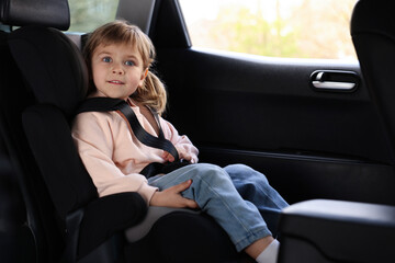 Little girl sitting in child safety seat inside car