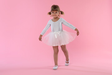Cute little girl dancing on pink background