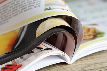 One open magazine on wooden table, closeup