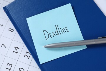 Sticky note with word Deadline, notebook, pen and calendar on table, top view