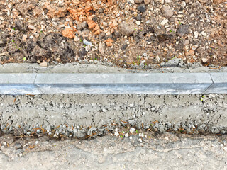 The construction progress is evident as a solid concrete curb runs alongside freshly excavated...