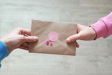 Transfers a letter in a craft envelope from hand to hand. Mail recipient.