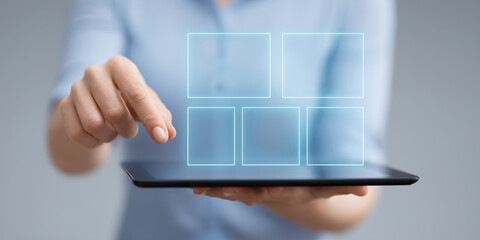 A woman in a blue shirt holds a tablet with a holographic interface. A concept of future technology and business management for a digital services promo