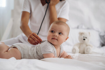 Listening to heartbeat by using stethoscope. Close up of nurse that is checking newborn baby