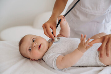 Listening to heartbeat by using stethoscope. Close up of nurse that is checking newborn baby