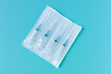 Syringes for injections in a package. Blue background.