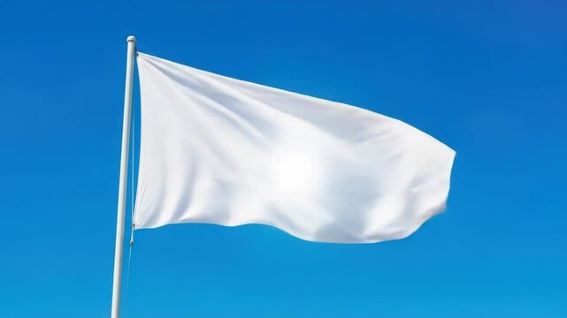 Waving white flag against clear blue sky conveys surrender, peace, or blank canvas concept.