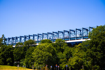Blue Truss Bridge Above Green Trees and Road Signs