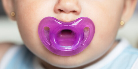 Close-up of baby with purple silicone pacifier