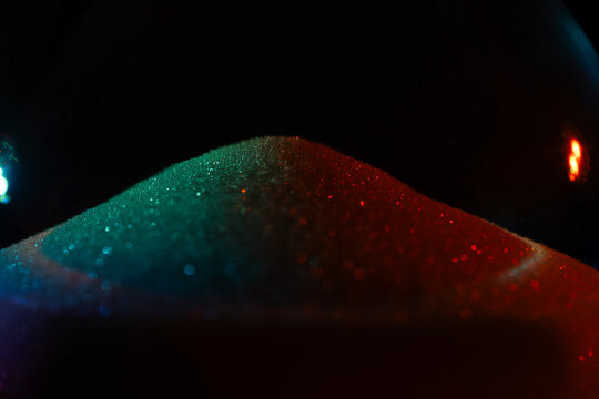 Rainbow sparkly hourglass sand on dark background. Minimalist low key poto for concepts of time, travel to the desert