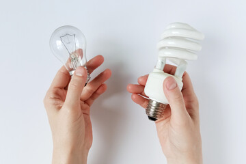 Incandescent lamp and energy saving lamp in hands of Caucasian woman. Concept energy resources. White background.