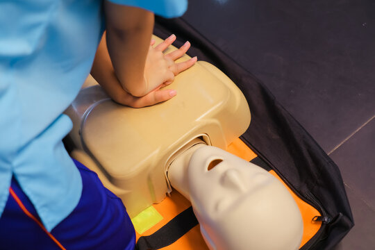 A person performs CPR chest compressions on a during a training session, highlighting essential life-saving techniques and emergency preparedness. - Powered by Adobe