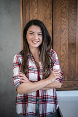 Confident young woman smiling with crossed arms in modern kitchen
