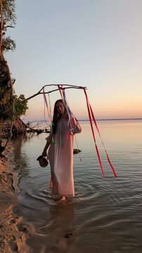 Ukrainian girl in wreath poses near water.