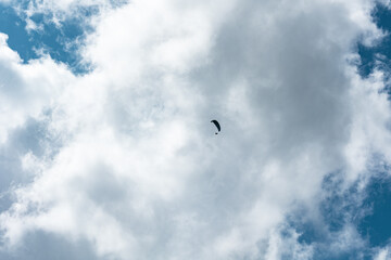 Paraglieder flies in the sky on a sunny day, clouds in the background, Switzerland, Swiss Alps....
